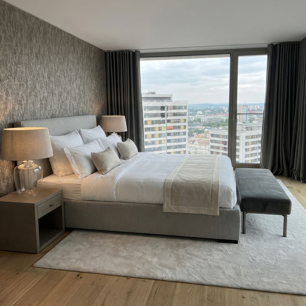 Ruhig gestaltetes Schlafzimmer mit gepolstertem Bett, neutralen Textilien und warmen Naturtönen – Interior Design von Hendrik Ritschel